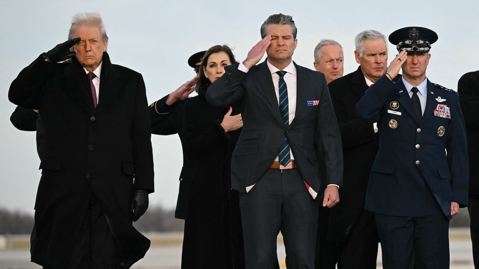 US President Donald Trump, Defense Secretary Pete Hegseth and Chairman of the Joint Chiefs of Staff Gen. Dan Caine salute during a ceremony for the return of the remains of two Iowa National Guard members and a translator killed in an attack in Syria at Dover Air Force Base in Delaware on December 17, 2025. (Photo by ANDREW CABALLERO-REYNOLDS / AFP via Getty Images)
