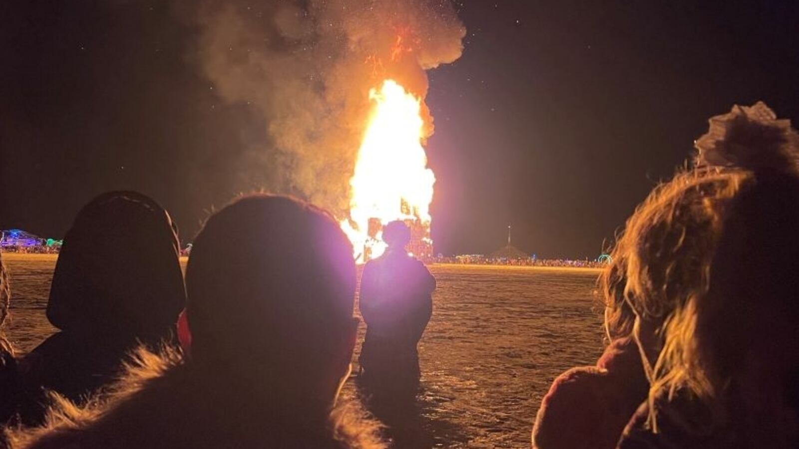 Attendees gather to watch the burning of "The Chapel of Babel," a work of art by Michael Burlington, during the annual Burning Man Festival in the early morning of September 5, 2023. Thousands of revelers stuck in the mud for days at the Burning Man festival in the US state of Nevada were told they could finally trek home on September 4, 2023, after torrential rain had prompted shelter-in-place orders. With the sun shining on the colorful makeshift community of 70,000 people called Black Rock City, the roads opened Monday afternoon, kicking off the official exit process known as the "Exodus." (Photo by Julie JAMMOT / AFP) (Photo by JULIE JAMMOT/AFP via Getty Images)