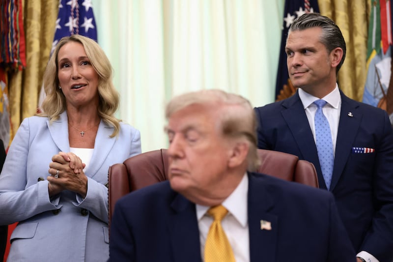 Jennifer Rauchet, wife of U.S. Secretary of Defense Pete Hegseth, speaks as U.S. President Donald Trump listens during an event to sign an executive order establishing the President's Military Spouse Commission to be chaired by Rauchet in the Oval Office at the White House in Washington, D.C., U.S., August 3, 2026.