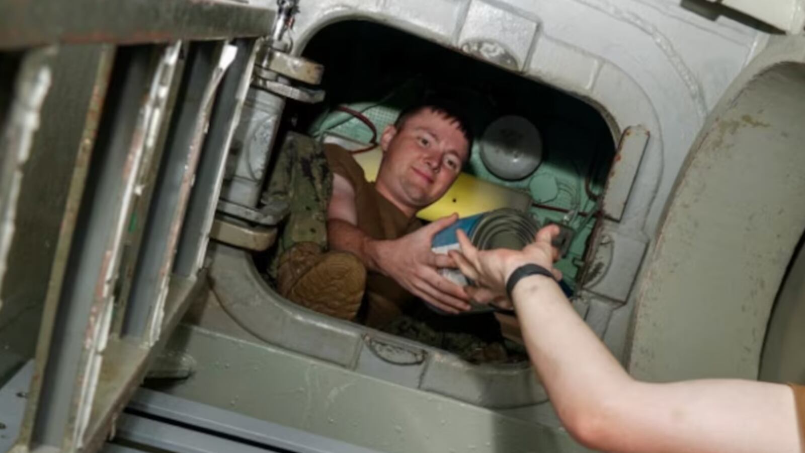 A picture of Andrew Taylor Wood being handed a can of food aboard the USS Key West.