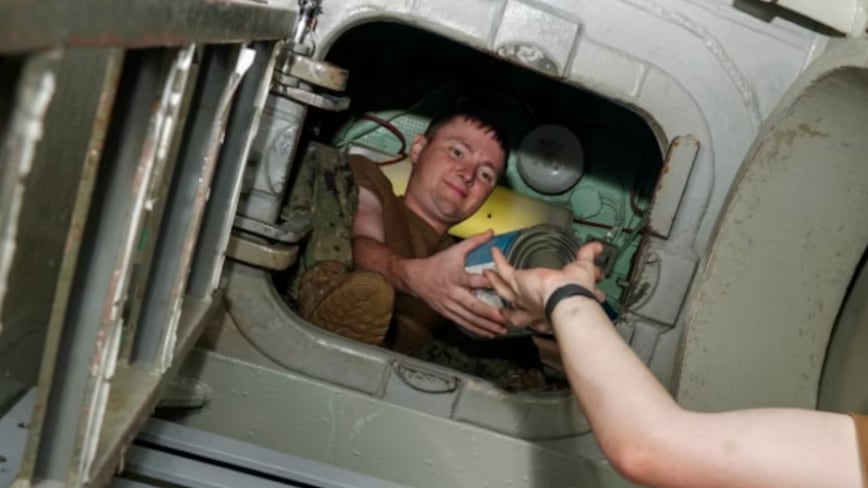 A picture of Andrew Taylor Wood being handed a can of food aboard the USS Key West.
