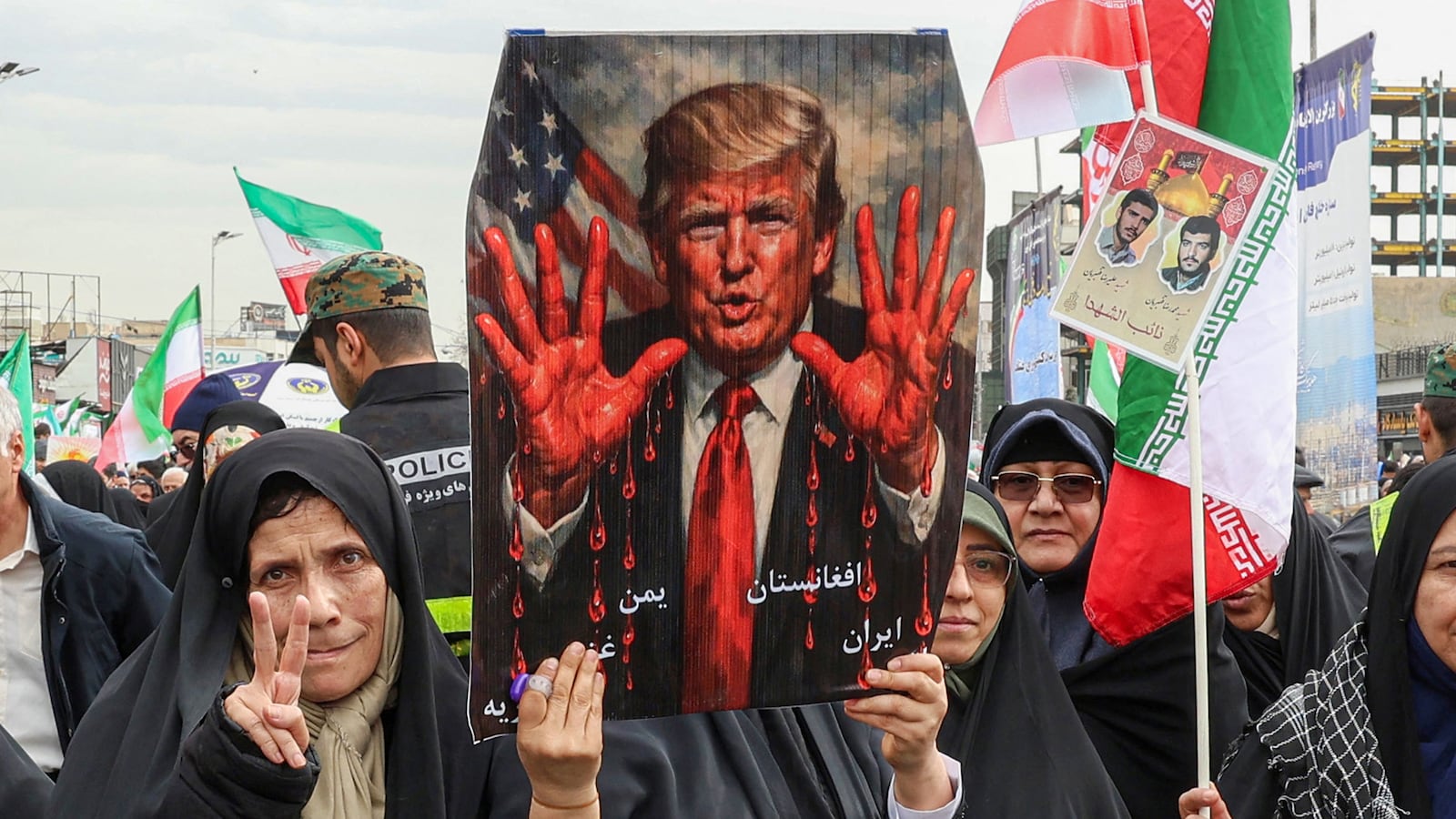 TOPSHOT - Women march with a sign depicting US President Donald Trump with bloodied hands in Tehran on February 11, 2026, during a rally marking the 47th anniversary of the 1979 Islamic revolution. The Persian calendar date of Bahman 22 celebrates the anniversary of the resignation of the ousted shah's last prime minister and the formal assumption of power by revolutionary leader Ayatollah Ruhollah Khomeini. (Photo by AFP via Getty Images)
