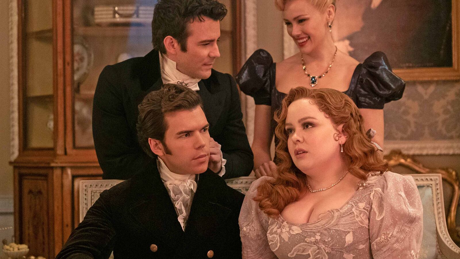 The cast of Bridgerton sit on a couch.