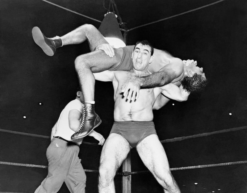 Grim faced Antonio Rocca applies a back-breaker to heavyweight wrestling champion Lou Thesz to win the second fall at Griffith Stadium. Thesz had pinned muscular Rocca down in the first fall making the match a draw.