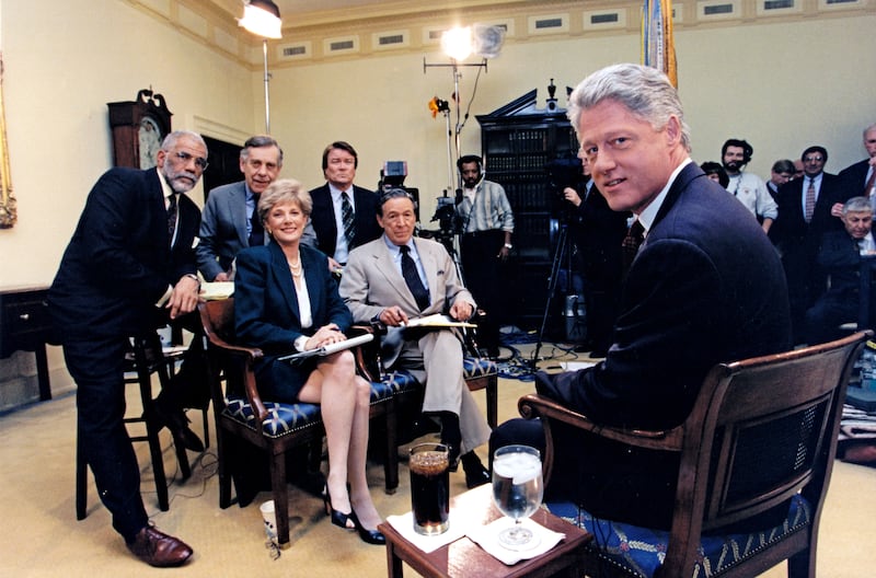 President Bill Clinton (right) poses for a photo as he records an interview with the CBS program '60 Minutes' in the White House's Roosevelt Room, Washington DC, December 8, 1995. Among those pictured are CBS' Ed Bradley, Morley Safer, Lesley Stahl, Steve Kroft, and Mike Wallace.