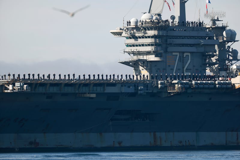 Sailors man the rails as the U.S. Navy Nimitz-class aircraft carrier USS Abraham Lincoln (CVN 72) is guided by tugboats in San Diego Bay as it returns to its homeport of Naval Air Station North Island after a 5-month deployment to the Middle East on December 20, 2024 in San Diego, California.