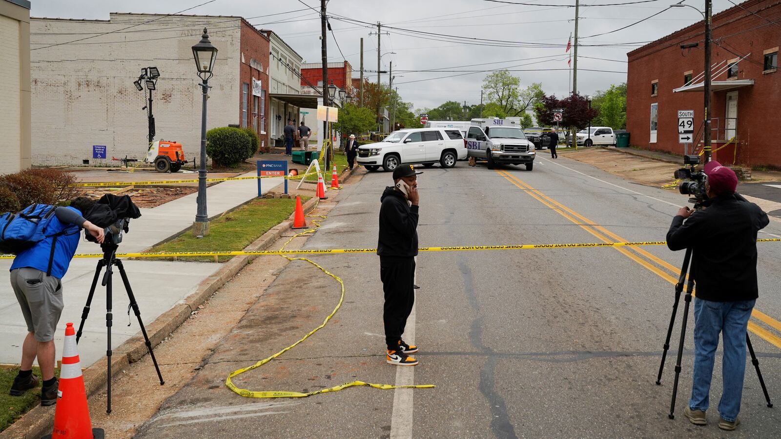 Community members and media stand near the crime scene, a day after a shooting at a teenager's birthday party in a dance studio, in Dadeville, Alabama.