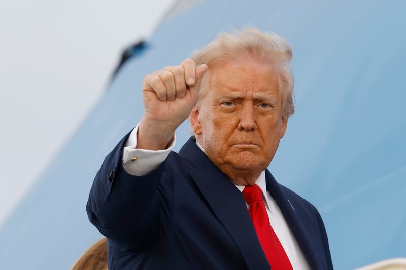 President Donald Trump raises his fist as he boards Air Force One to depart the UK on September 18, 2025 in Stansted, England.