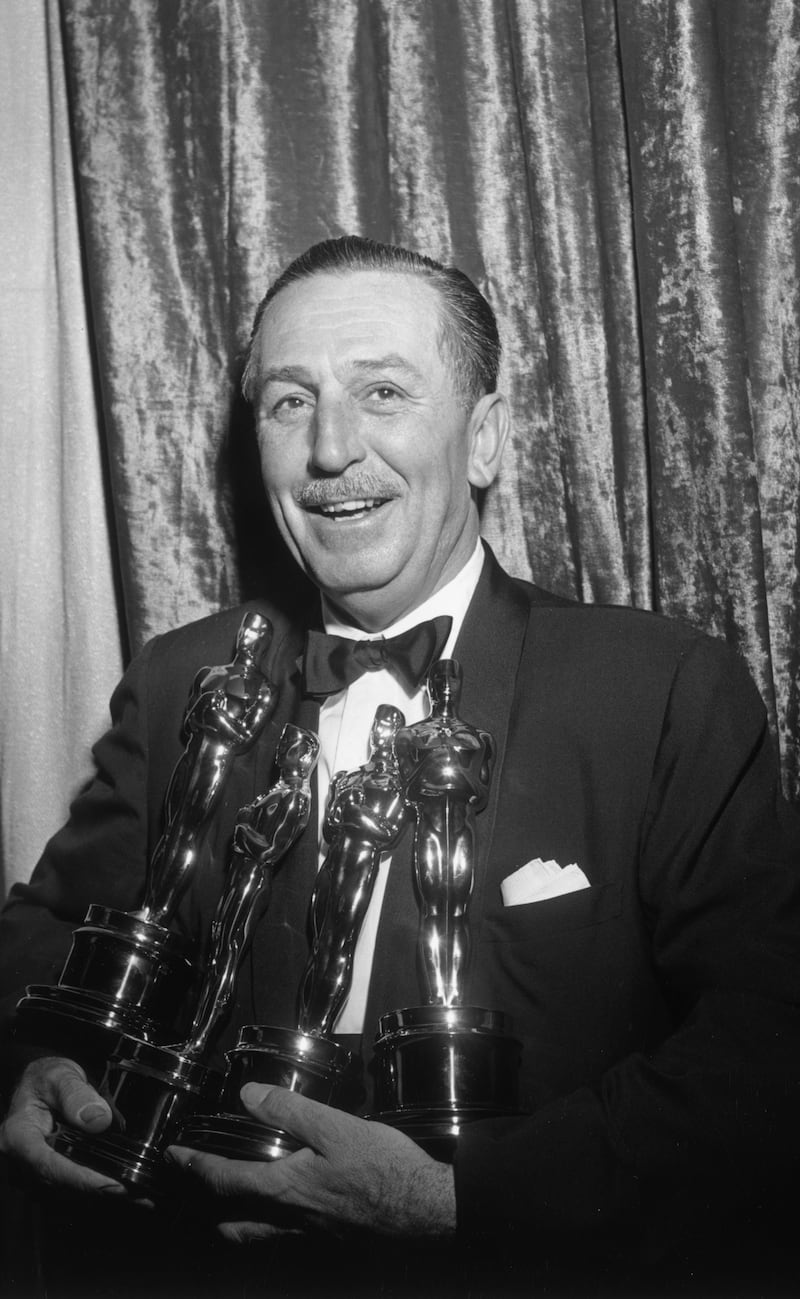 Walt Disney holding four Oscars in 1954