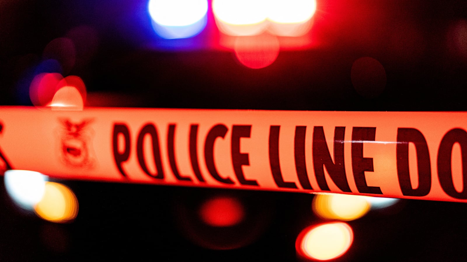 Police tape in front of lights from a police car.