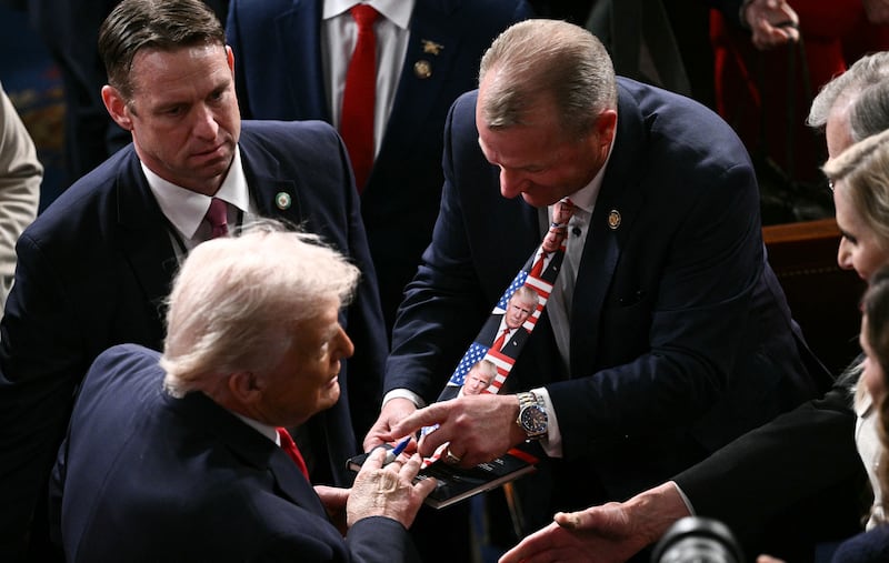 President Donald Trump signs a tie at his effigy worn by US Representative Troy Nehls, Republican of Texas, as he departs the House Chamber of the US Capitol in Washington after delivering the State of the Union address, February 24, 2026. (Photo by Brendan SMIALOWSKI / AFP via Getty Images)