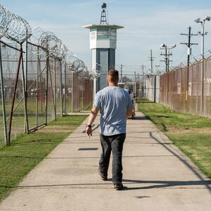 ANGOLA PRISON, LOUISIANA - OCTOBER 14, 2013:  A prisoner walks thru a fenced section toward a guard tower at Angola Prison

The Louisiana State Penitentiary, also known as Angola, and nicknamed the "Alcatraz of the South" and "The Farm" is a maximum-security prison farm in Louisiana operated by the Louisiana Department of Public Safety & Corrections. It is named Angola after the former plantation that occupied this territory, which was named for the African country that was the origin of many enslaved Africans brought to Louisiana in slavery times.

This is the largest maximum-security prison in the United States[with 6,300 prisoners and 1,800 staff, including corrections officers, janitors, maintenance, and wardens. It is located on an 18,000-acre (7,300 ha) property that was previously known as the Angola Plantations and bordered on three sides by the Mississippi River.

(Photo by Giles Clarke/Getty Images)