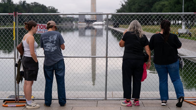 People visit the fenced-off Reflecting Pool