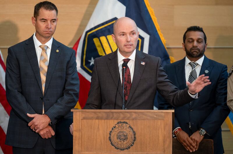 A sheepish  FBI Director Kash Patel, back right, appears alongside Utah Governor Spencer Cox, front, and Utah Department of Public Safety Beau Mason during a press conference announcing details on the suspect in the shooting of U.S. conservative commentator Charlie Kirk.