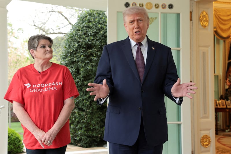 President Donald Trump speaks with the media next to Sharon Simmons after receiving a McDonald's order via DoorDash, which she delivered to him in front of the Oval Office at the White House in Washington, D.C., U.S., April 13, 2026.