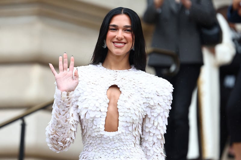 Singer Dua Lipa waves at the camera.