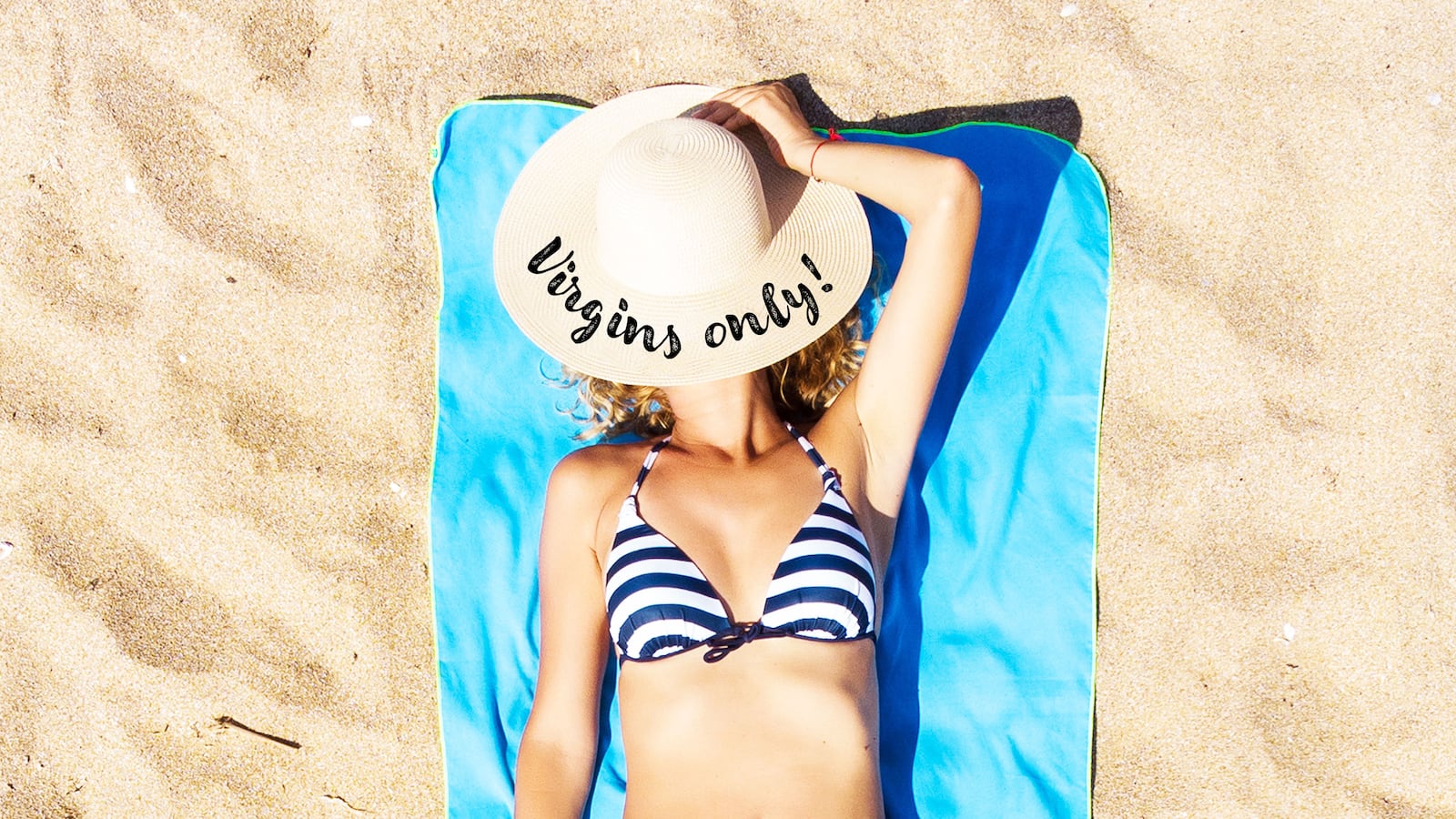 A woman on the beach lays on a towel with a hat that says ‘Virgins Only’