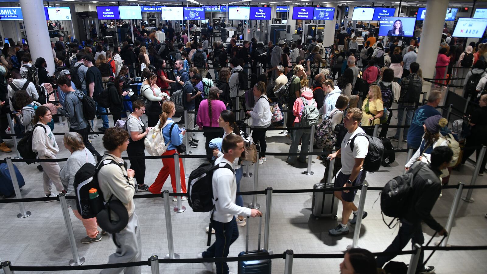 Travelers move through a TSA security screening line at Orlando International Airport on the day before Thanksgiving in Orlando, Florida, United States, on November 26, 2025.