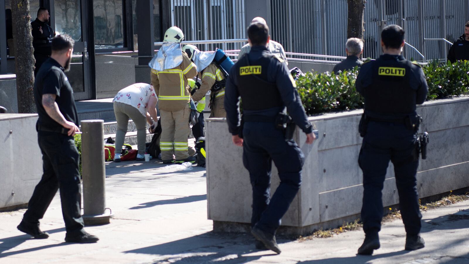 Police officers and firefighters help a 18-year old man who set himself on fire in front of the U.S. Embassy in Copenhagen, Denmark, April 21, 2023.