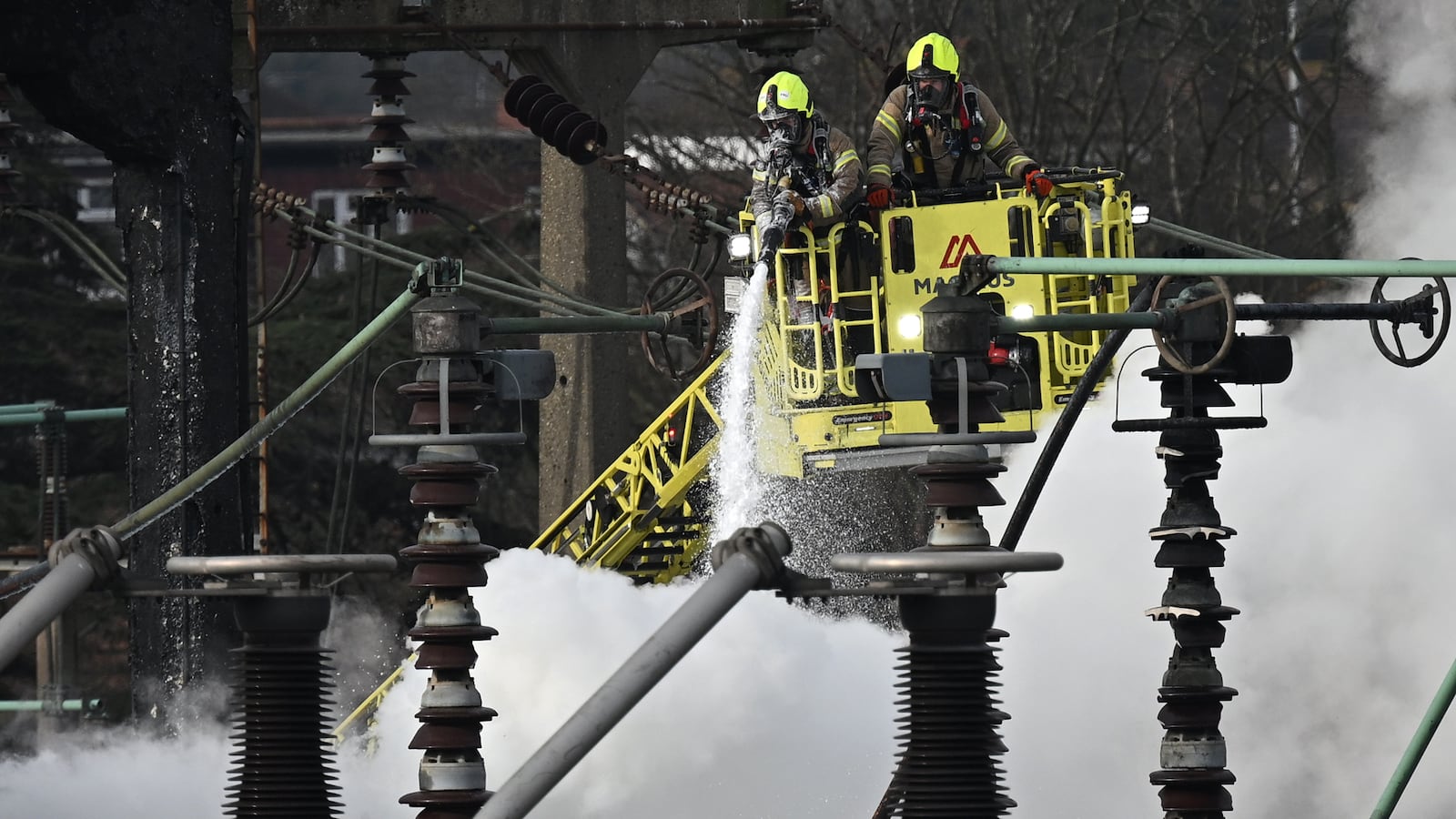 Two firefighters in a crane spray foam on a fire at an electrical substation at London Heathrow Airport.