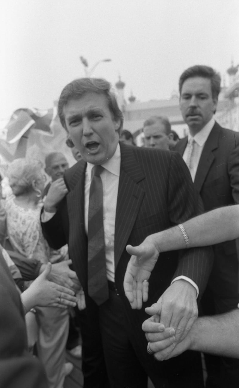 Trump in black and white with hands trying to shake his