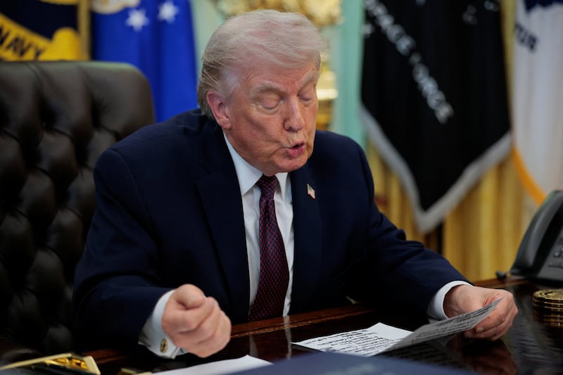 President Donald Trump reads from his oversized notes in the Oval Office.