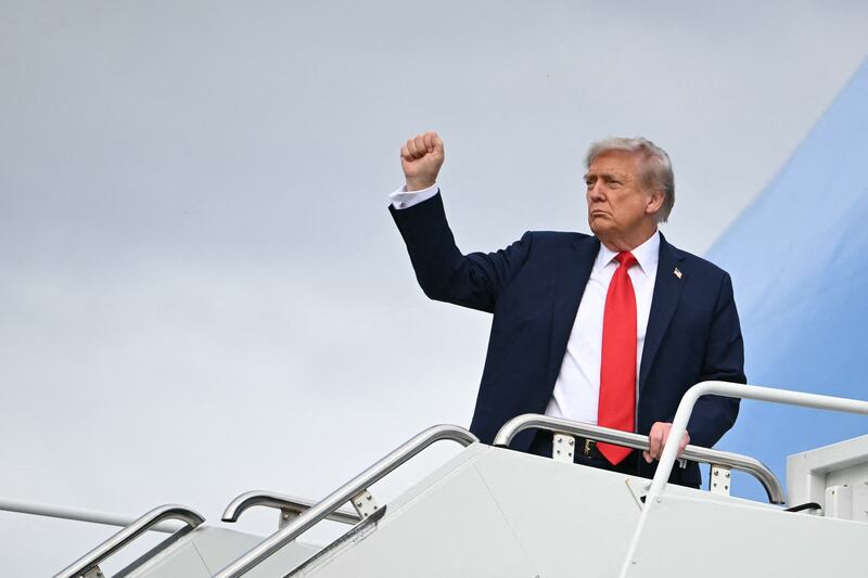 President Donald Trump raises a fist as he boards Air Force One before departing from Anchorage, Alaska after a summit with the Russia's Vladimir Putin on August 15, 2025.
