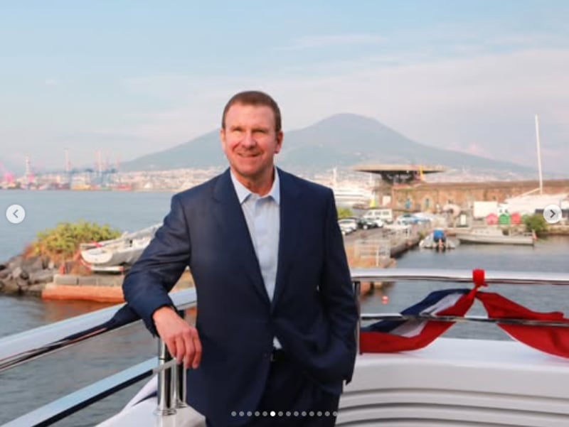 Tilman Fertitta on the deck of his yacht with Mount Vesuvius in the background.