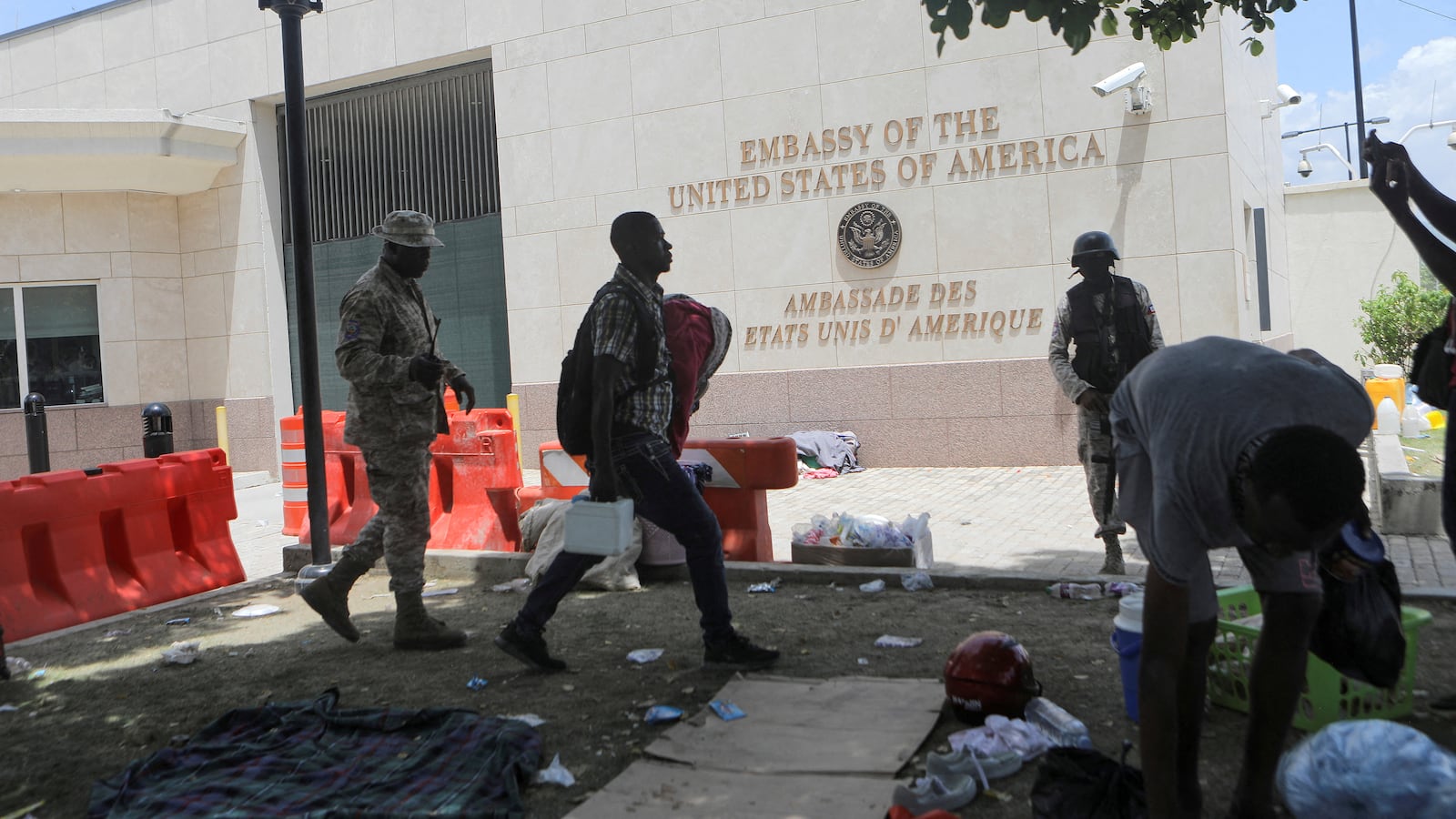 A man carries his belongings after officers of the Haitian National Police fired tear gas to clear a camp of people escaping the threat of armed gangs, in front of the U.S. Embassy, in Port-au-Prince, Haiti, July 25, 2023.