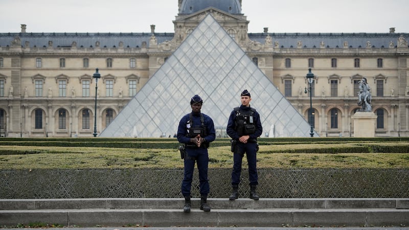 Police stand guard outside the Louvre museum at Louvre on October 19, 2025 in Paris, France.