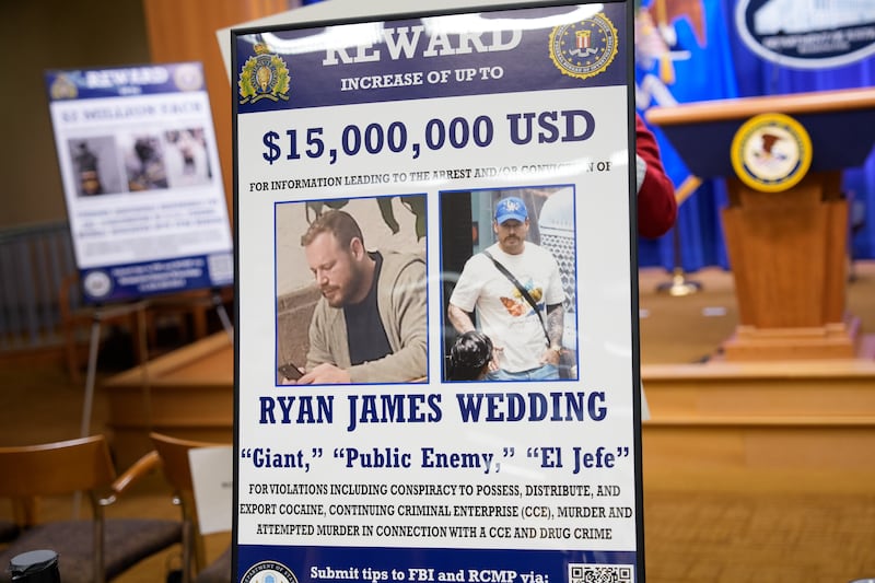 A reward poster for the arrest of Ryan Wedding is visible following a news conference announcing the indictment of a former Olympic snowboarder Ryan Wedding, charging him with murder and money laundering in connection to a drug trafficking organization at the Justice Department on November 19, 2025 in Washington, DC.
