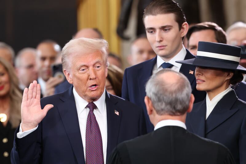 Donald Trump takes the oath of office as Barron Trump and Melania Trump look on