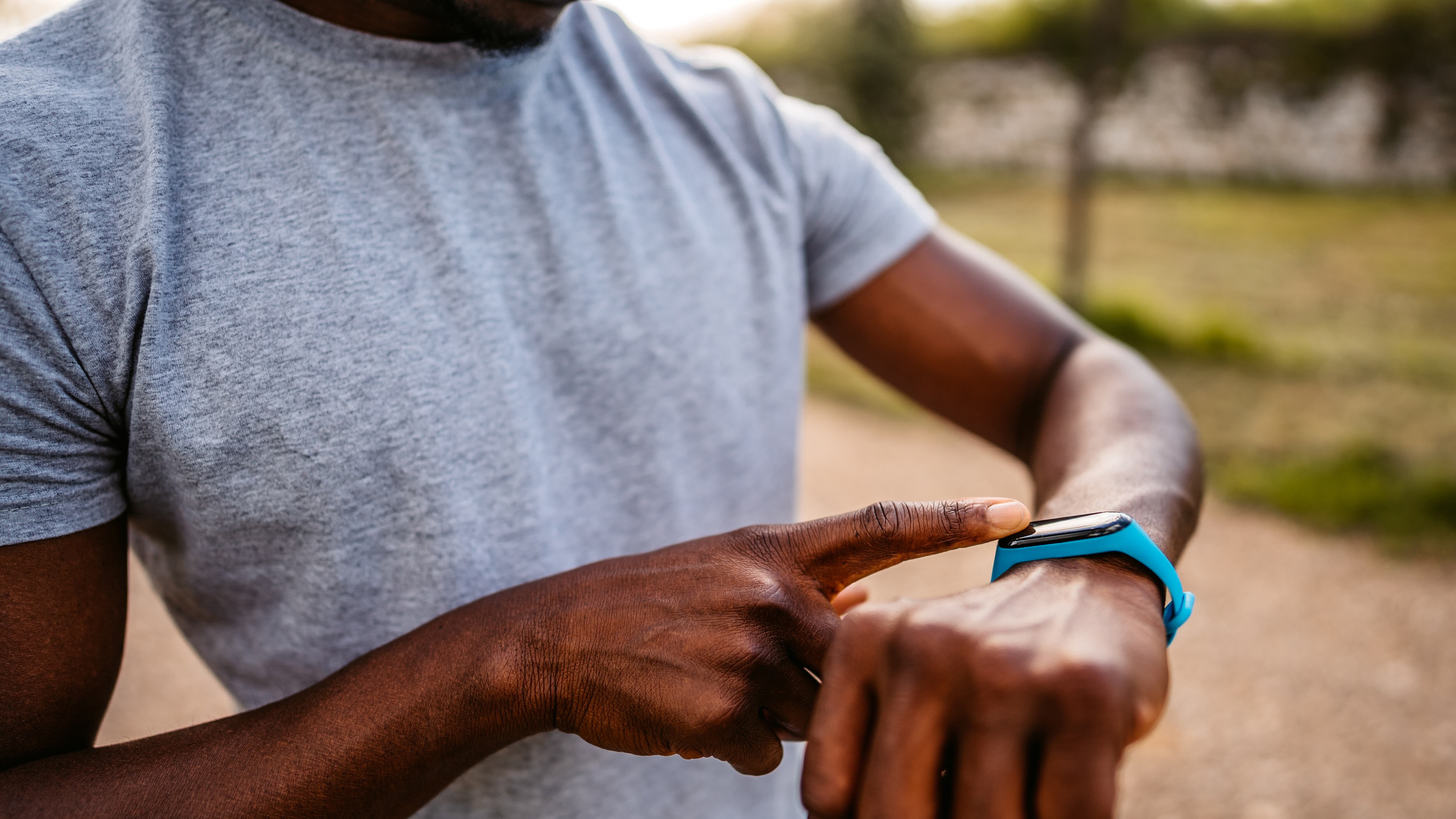 Athlete check fitness tracker on smartwatch or playing his music playlist after training in nature.