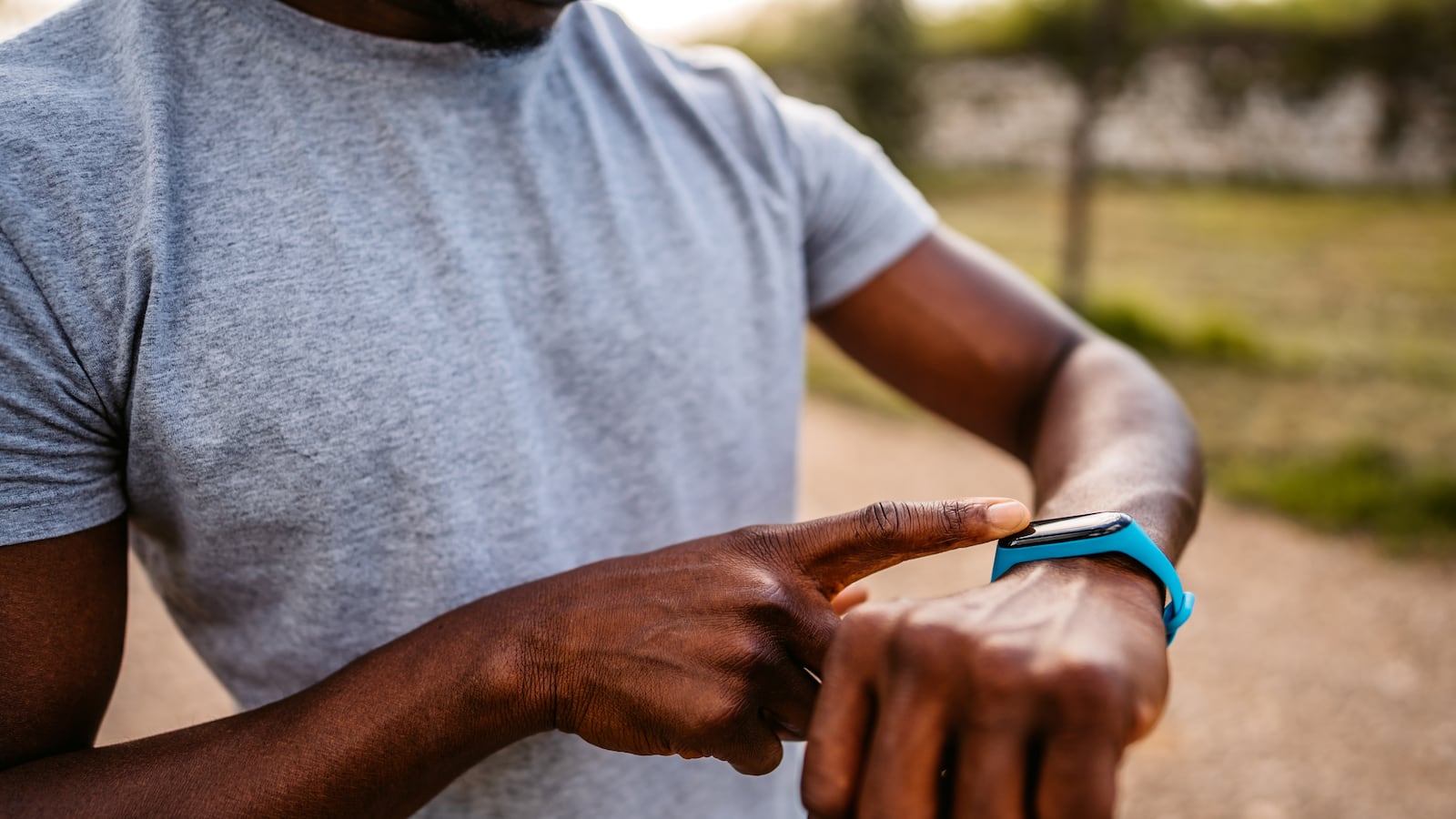 Athlete check fitness tracker on smartwatch or playing his music playlist after training in nature.