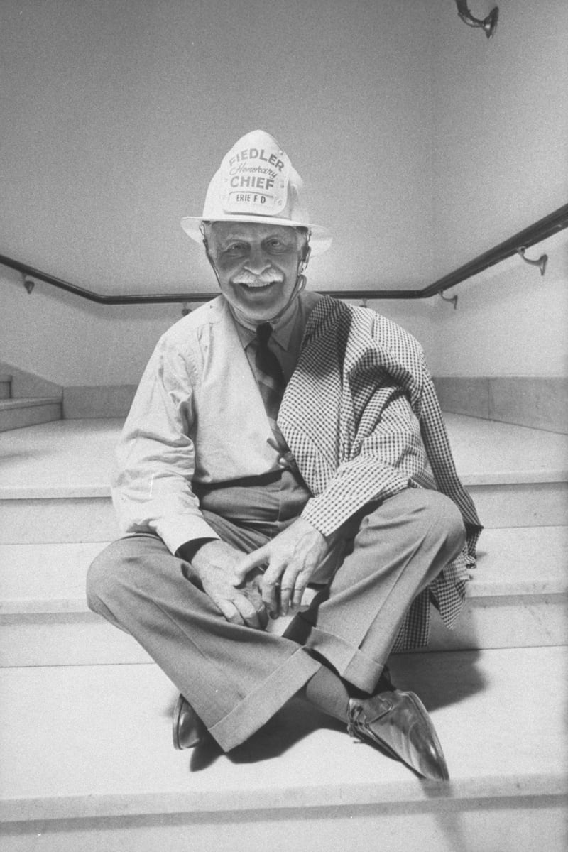 Boston Pops conductor Arthur M. Fielder wearing one of his collection of 400 firemen's helmets.