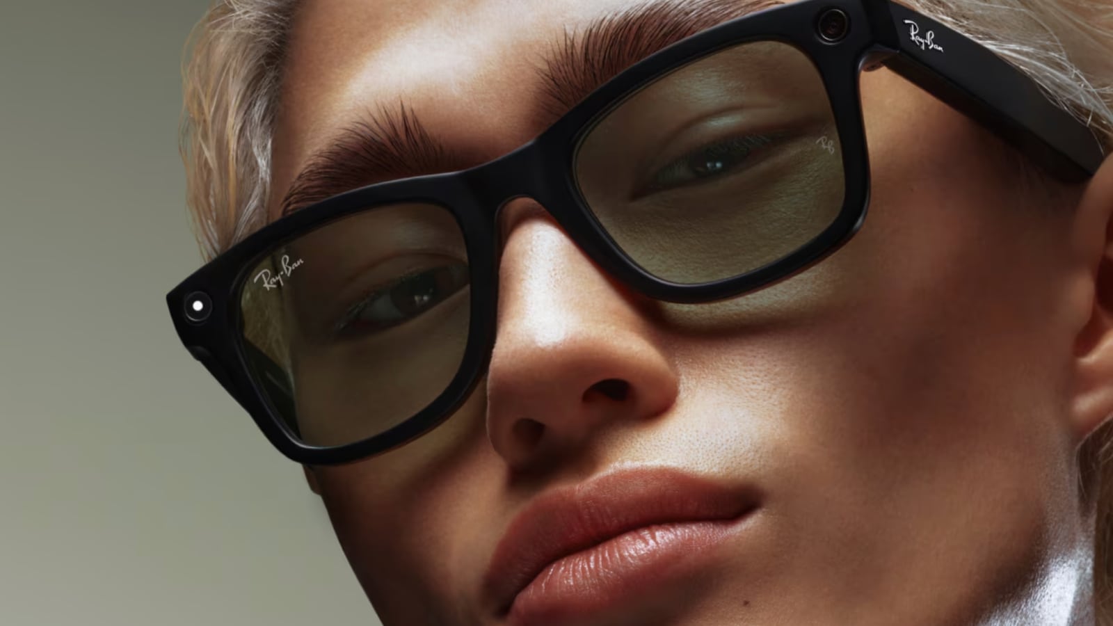 A person with blonde hair wearing a pair of Ray-Ban Meta Wayfarer smart glasses.