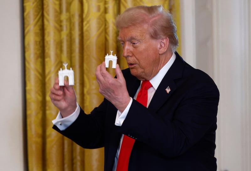 WASHINGTON, DC - OCTOBER 15: U.S. President Donald Trump holds models of an arch as he delivers remarks during a ballroom fundraising dinner in the East Room of the White House on October 15, 2025 in Washington, DC. Trump hosted organizations and individuals for a fundraising dinner for the new $250 million ballroom addition currently under construction at the White House. (Photo by Kevin Dietsch/Getty Images)