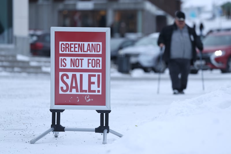 A man walks near a sign that reads: "Greenland Is Not For Sale!" on January 21, 2026 in Nuuk, Greenland.