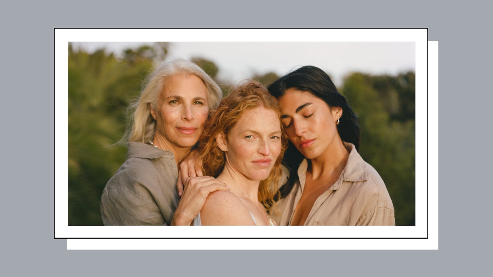 Three women with long hair posing outside for a photo.