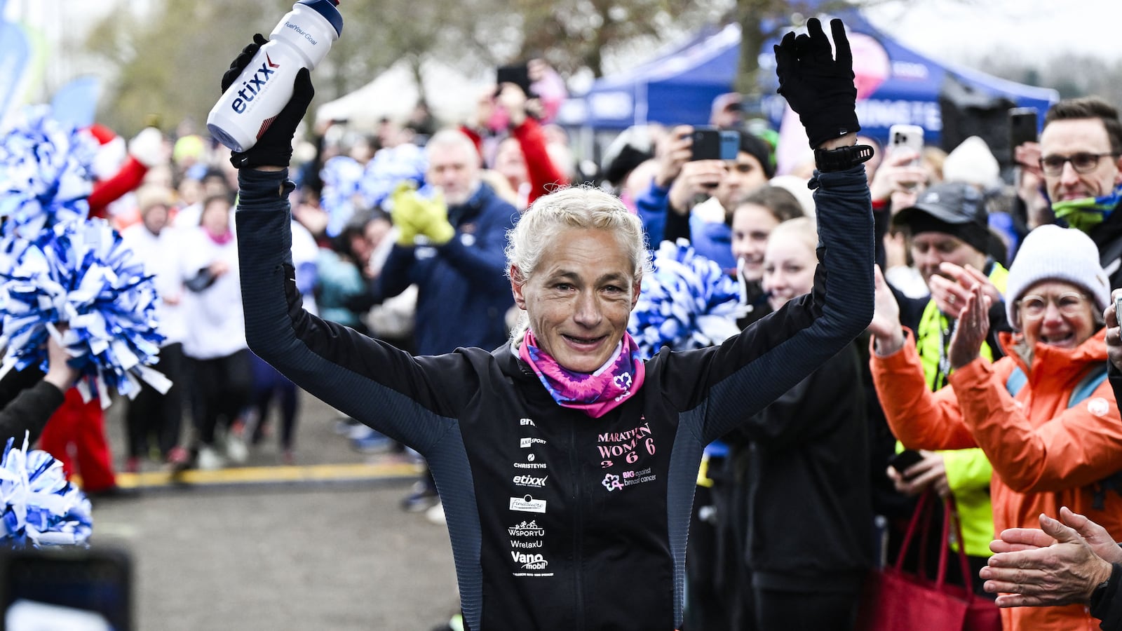 Supporters look on as runner Hilde Dosogne celebrates after crossing the finish line of her 366th marathon in Ghent, Belgium on December 31, 2024.