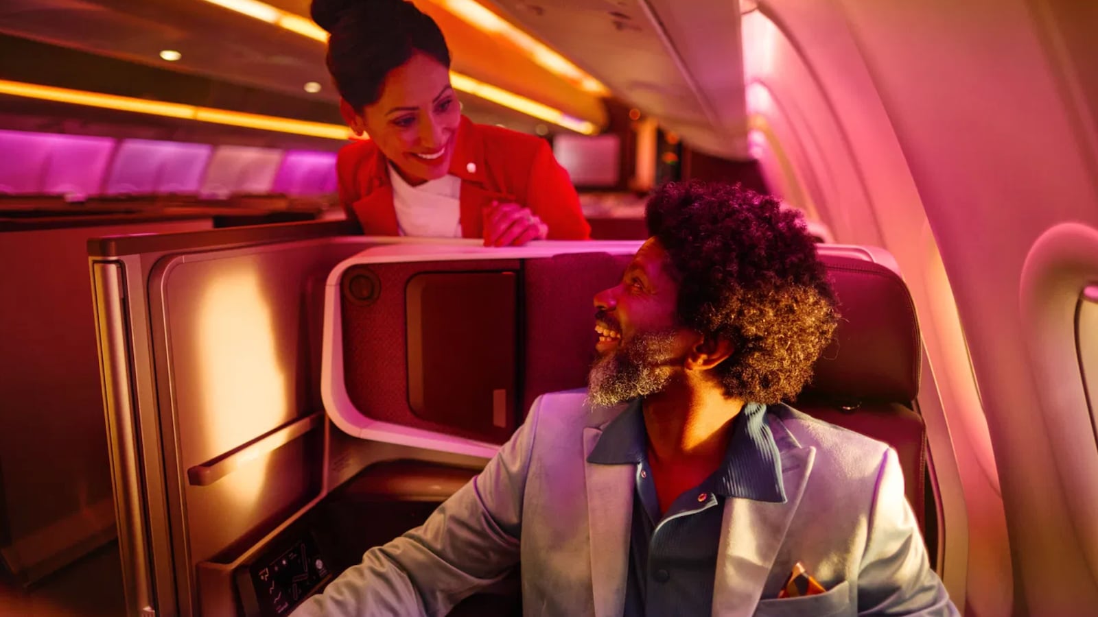A man on a plane talking to a stewardess.