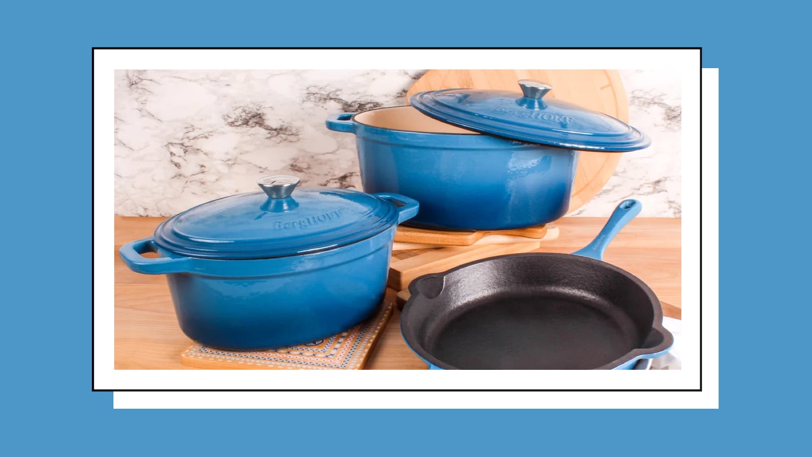 A set of two blue dutch ovens and a blue frying pan on a table.