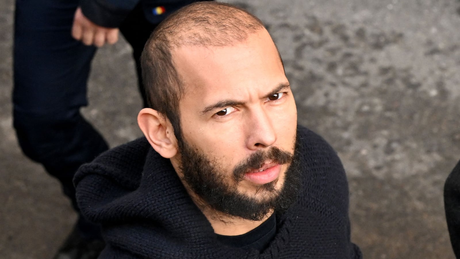 British-US influencer Andrew Tate arrives handcuffed and escorted by police at a courthouse in Bucharest on February 1, 2023.