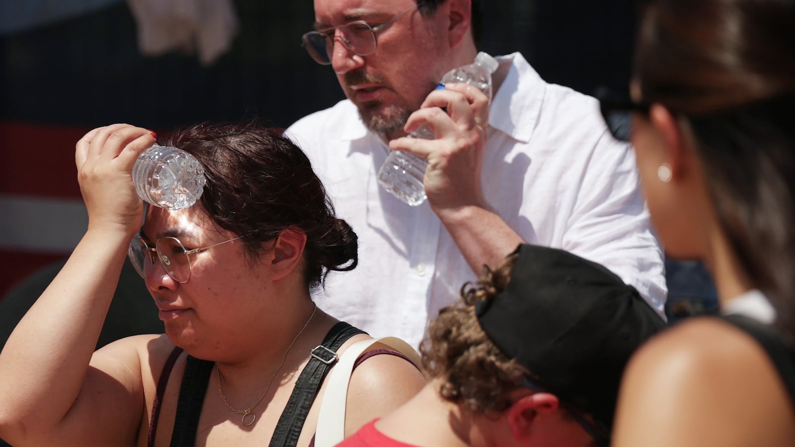 People cool themselves with an ice-cold water bottle from a water station during a heat wave in Washington, D.C.
