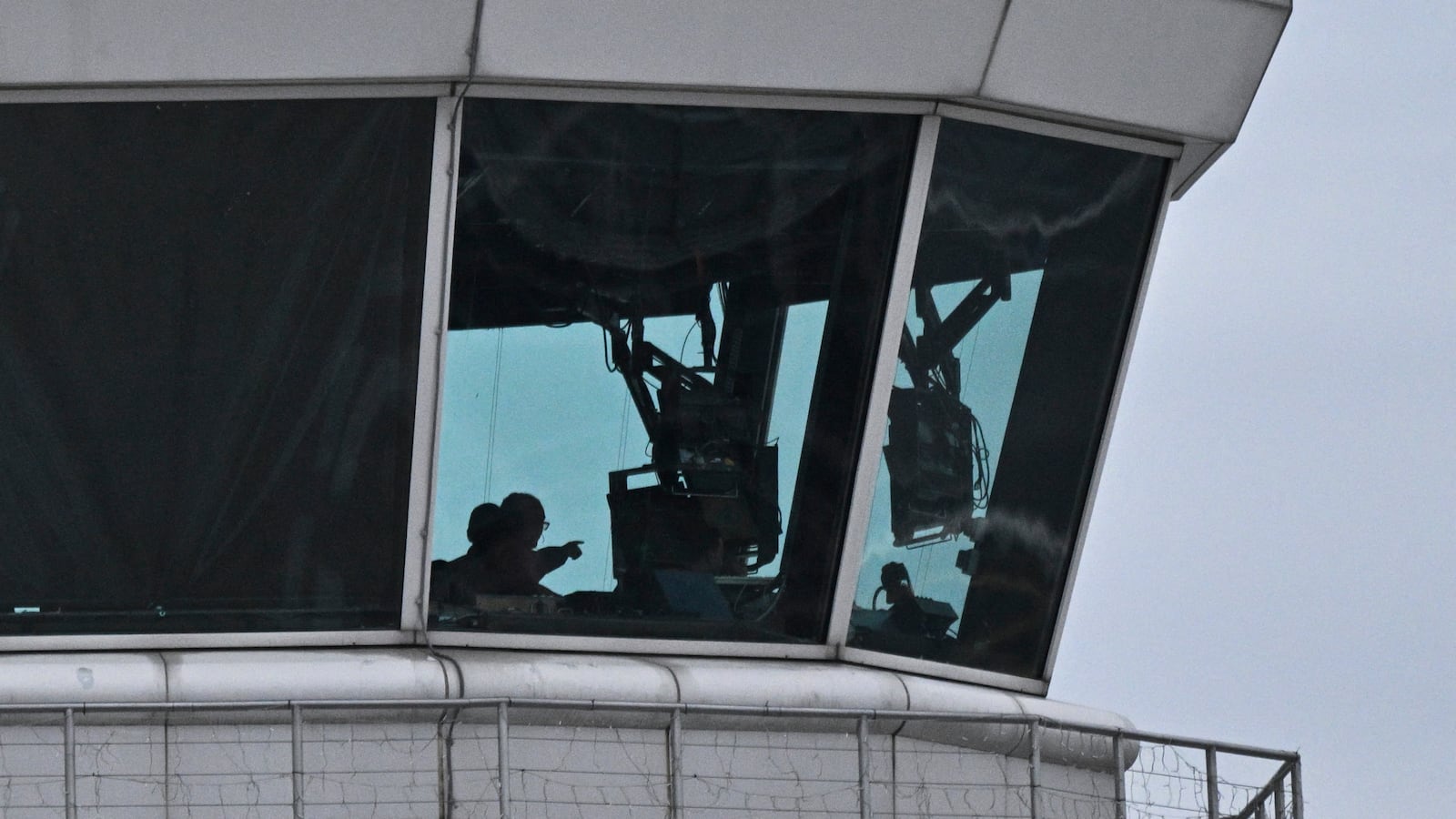 Air controllers work in the control tower of Ronald Reagan International Airport as recovery efforts by authorities for the remains of a commercial liner and a military helicopter that crashed earlier in the week continue on the nearby Potomac River in Arlington, Virginia, on February 2, 2025. Operations to salvage the wreckage from a deadly collision between a US Army helicopter and a passenger jet continued on February 2 as rescuers said 55 victims had so far been identified. Dozens of victims have been pulled from the icy Potomac River, and rescuers voiced confidence that those remaining would be retrieved in the massive operation to recover the plane that collided in midair with a Black Hawk military helicopter. (Photo by ROBERTO SCHMIDT / AFP) (Photo by ROBERTO SCHMIDT/AFP via Getty Images)