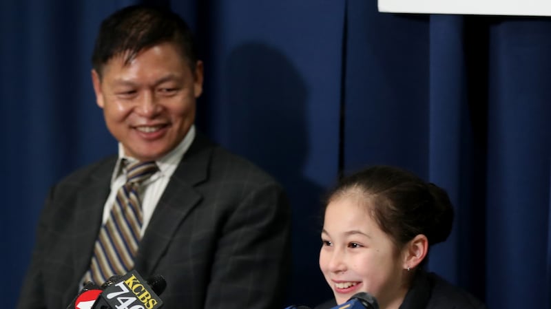 Alysa Liu, 13, of Richmond, center, along with her father Arthur Liu, and her coach Laura Lipetsky hold a press conference after practice at Oakland Ice Center
