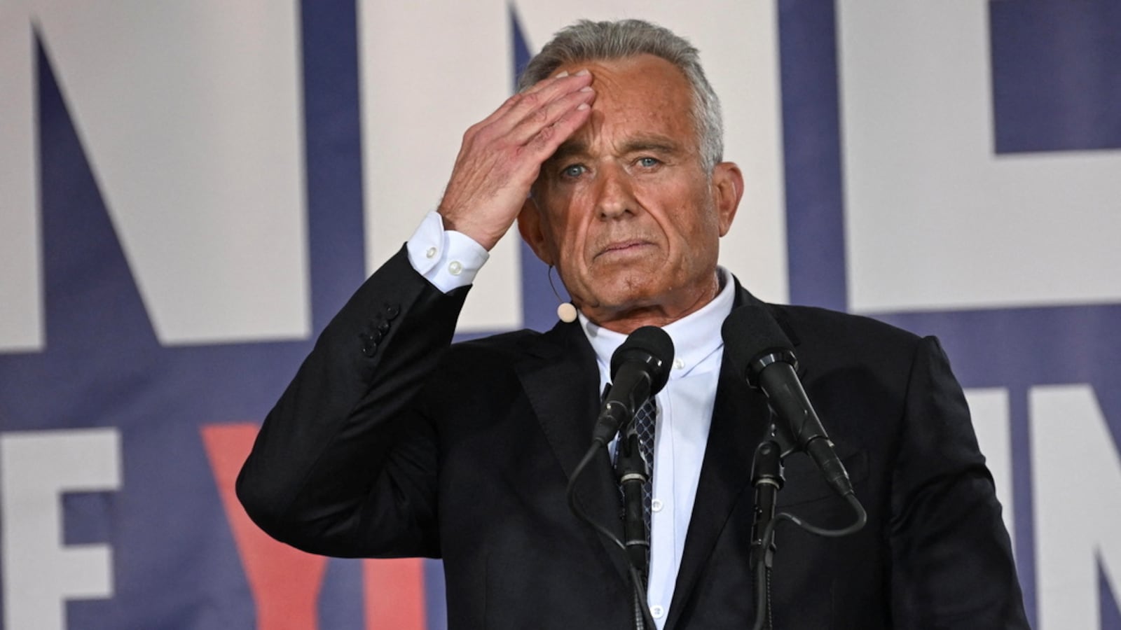 Robert F. Kennedy Jr. holding a hand to one temple at a campaign event.