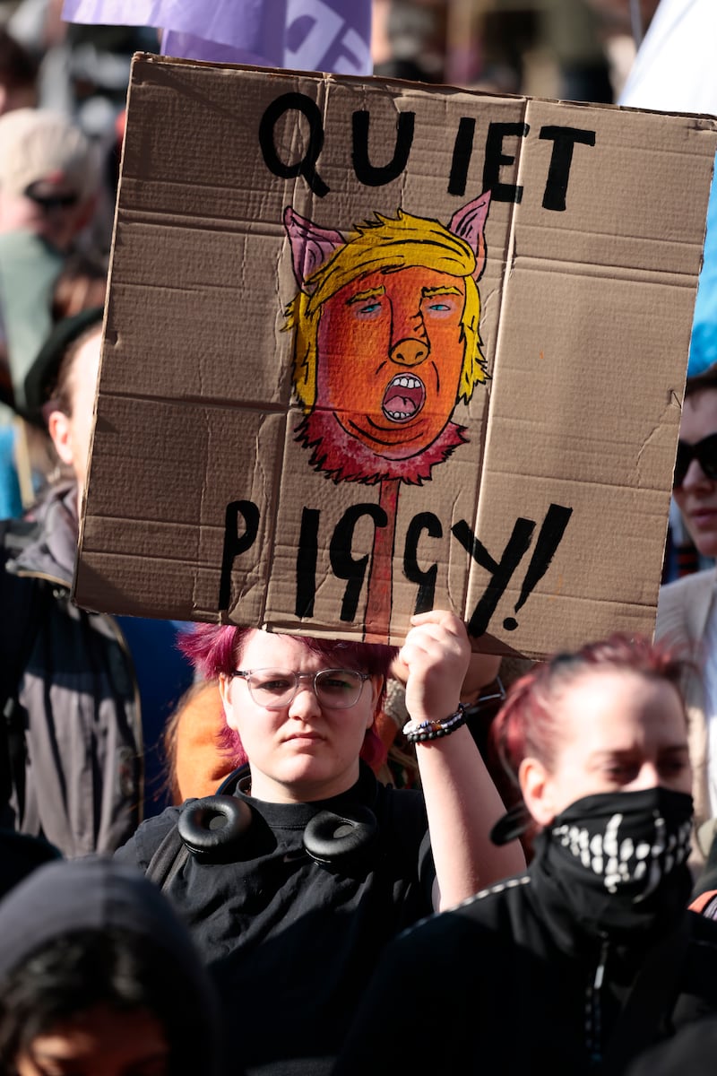 EDINBURGH, SCOTLAND - MARCH 21: A protester holds up a placard depicting Donald Trump with the words "Quiet Piggy" as they gather for the 'Unite The Clans' Rally and 'Stand Up To Racism' Counter-Protest at West Parliament Square before marching to Scottish Parliament building on March 21, 2026 in Edinburgh, Scotland. Unite the Clans Scotland is a right-wing movement stating opposition to mass immigration. Opposing today's rally is the group Stand Up To Racism. (Photo by Jeff J Mitchell/Getty Images)