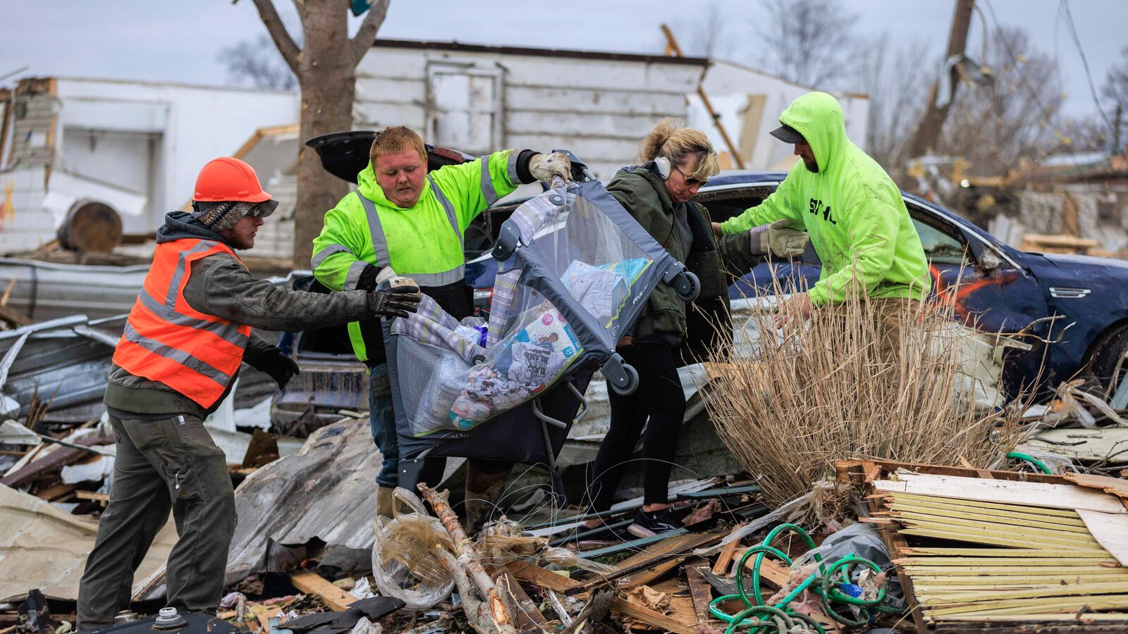 Volunteers help remove items from a damaged home for a family with a baby after a tornado.