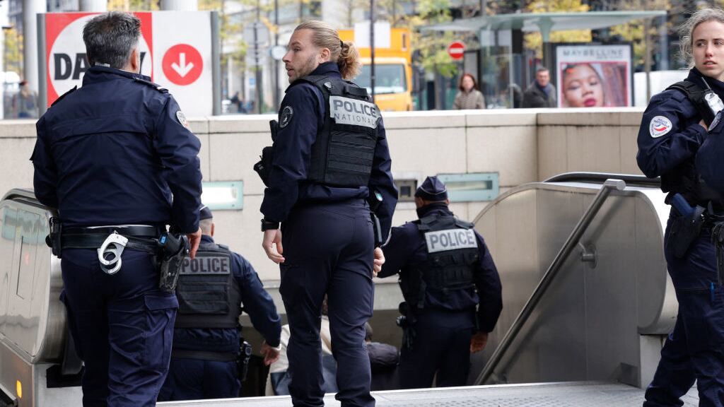 French police officers stand at the entrance of a metro station after a woman making threats on an RER train was shot and wounded by police, in Paris on October 31, 2023.